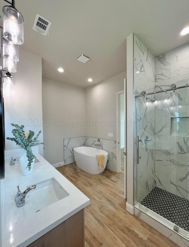 7504 Limestone Dr, Amarillo, TX 79119 - bathroom featuring wood finished floors, a freestanding tub, a marble finish shower, recessed lighting, and vanity