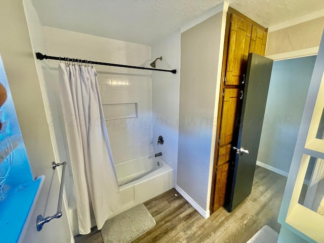 bathroom featuring baseboards, shower / tub combo with curtain, wood finished floors, and a textured ceiling