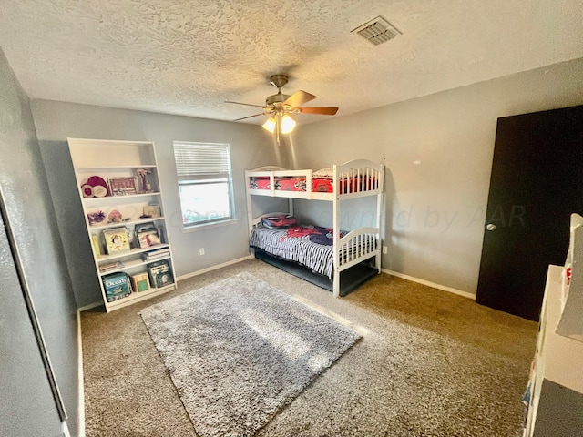 carpeted bedroom with a textured ceiling, visible vents, baseboards, and ceiling fan