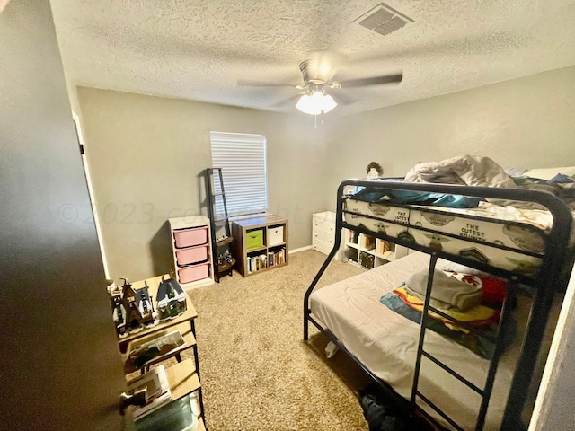 bedroom featuring a ceiling fan, a textured ceiling, visible vents, and carpet