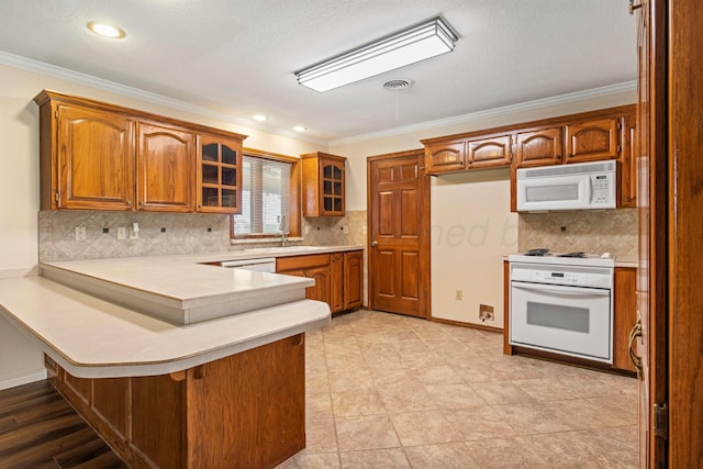 624 Nara Visa Ln, Fritch, TX 79036 - kitchen with white appliances, a peninsula, ornamental molding, brown cabinetry, and light countertops