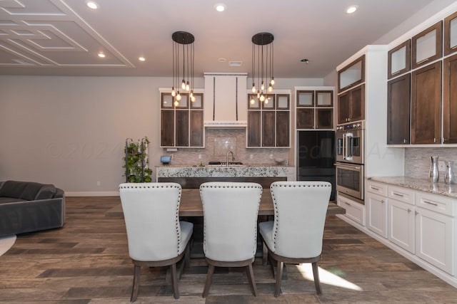 kitchen with recessed lighting, dark brown cabinets, glass insert cabinets, a center island, and tasteful backsplash