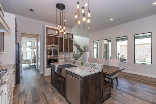kitchen with dark brown cabinets, dark wood-style flooring, stainless steel appliances, and a sink
