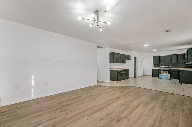unfurnished living room with light wood finished floors, visible vents, baseboards, a notable chandelier, and a sink