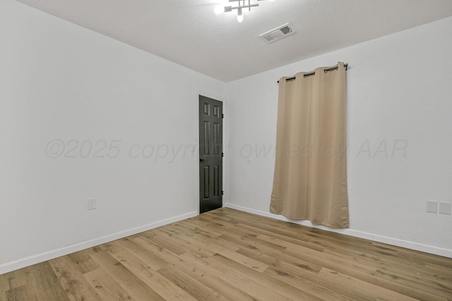 empty room featuring visible vents, baseboards, and light wood-style flooring