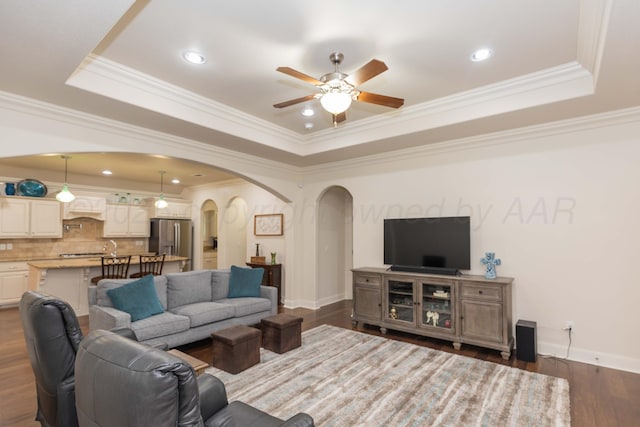 7901 Kingsgate Dr, Amarillo, TX 79119 - living area with arched walkways, a raised ceiling, a ceiling fan, crown molding, and dark wood-style flooring