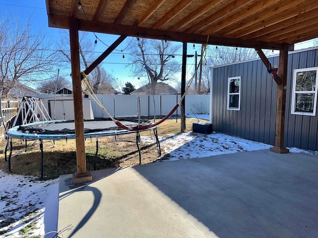 snow covered patio featuring a trampoline and a shed