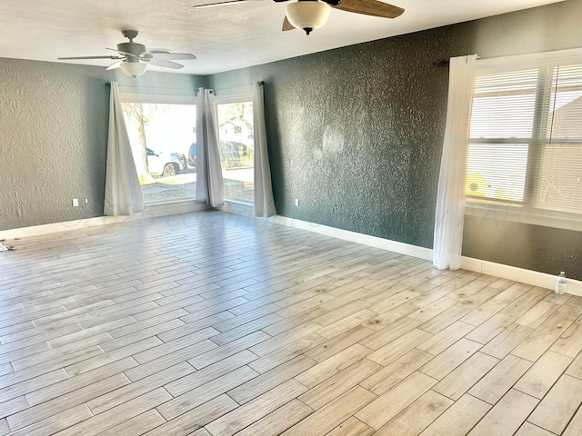 unfurnished room with a textured ceiling, light hardwood / wood-style flooring, and ceiling fan