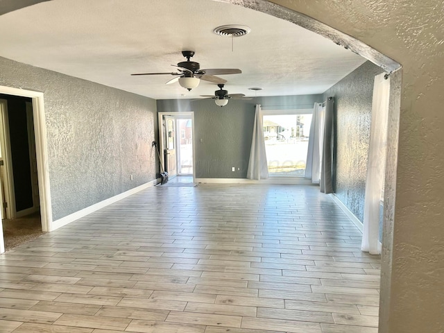 empty room featuring ceiling fan, light hardwood / wood-style flooring, and a textured ceiling