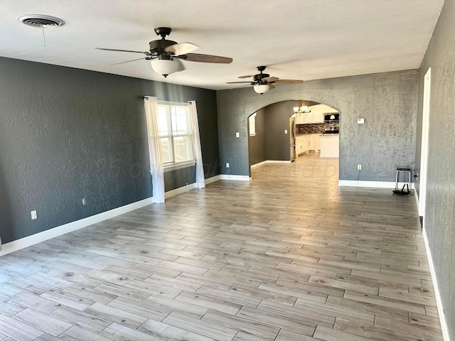 empty room with ceiling fan and light hardwood / wood-style flooring