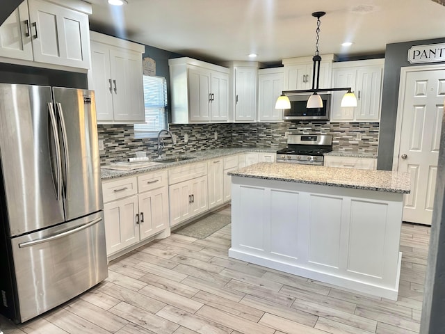 kitchen featuring white cabinetry, appliances with stainless steel finishes, light stone countertops, and pendant lighting