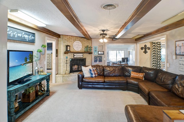 carpeted living room with a textured ceiling, a brick fireplace, beamed ceiling, and ceiling fan