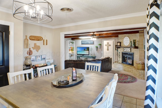 dining space with light tile patterned flooring, ornamental molding, ceiling fan with notable chandelier, a textured ceiling, and a brick fireplace