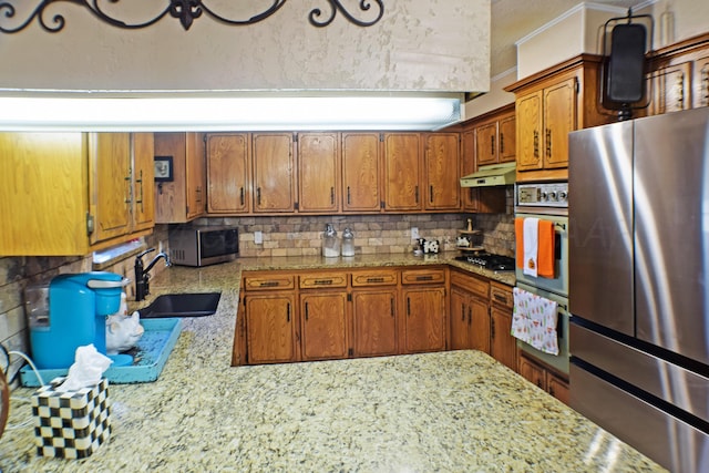 kitchen with stainless steel appliances, light stone countertops, sink, and backsplash