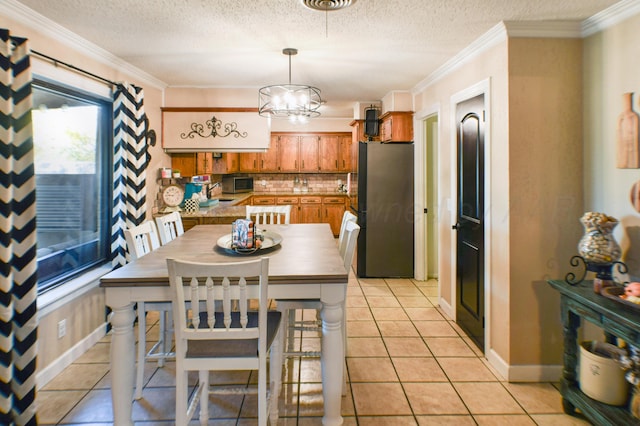 tiled dining space with a textured ceiling, a notable chandelier, and ornamental molding