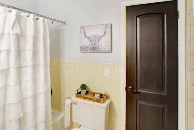 bathroom featuring toilet, tile walls, and shower / bathtub combination with curtain