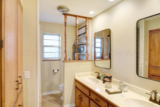 bathroom with toilet, vanity, and tile patterned flooring