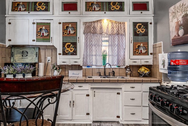 kitchen featuring tile countertops, white cabinetry, sink, backsplash, and light wood-type flooring