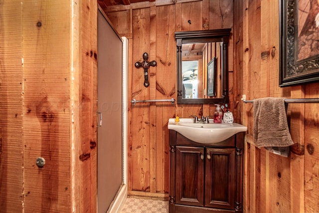 bathroom featuring walk in shower, wood walls, and vanity