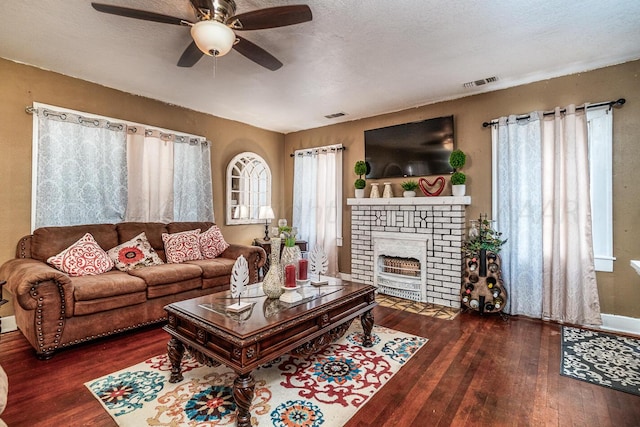 living room with a fireplace, ceiling fan, a textured ceiling, and dark hardwood / wood-style flooring