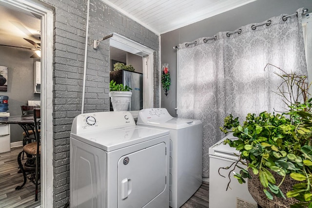 washroom featuring ornamental molding, hardwood / wood-style floors, independent washer and dryer, ceiling fan, and brick wall