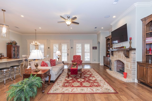 living room with hardwood / wood-style floors, ceiling fan with notable chandelier, and crown molding