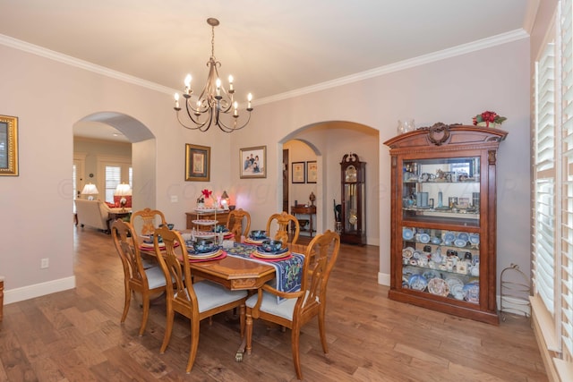 dining area with ornamental molding, wood-type flooring, and a chandelier