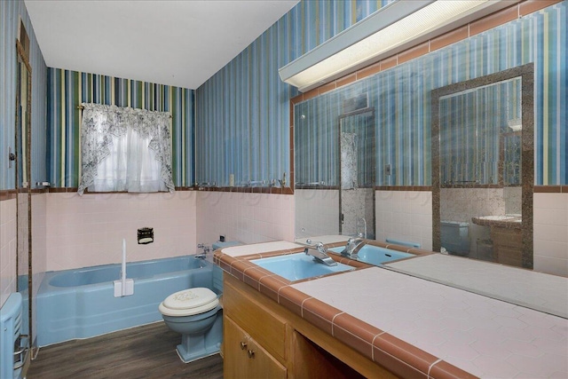 709 Franklin Ave, Panhandle, TX 79068 - full bathroom with wallpapered walls, wood finished floors, a bath, toilet, and wainscoting