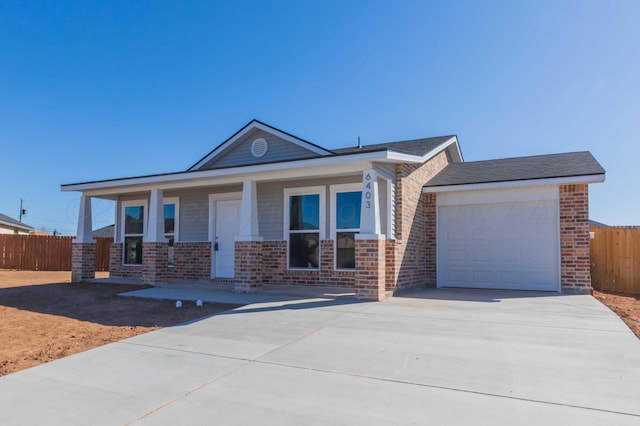 view of front facade featuring a garage, driveway, fence, and brick siding