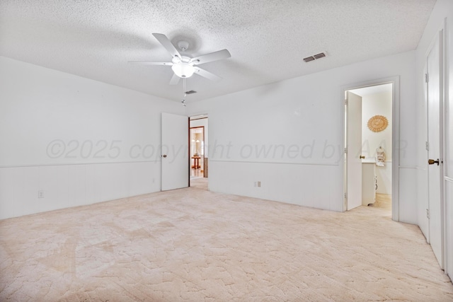 unfurnished room featuring carpet flooring, a ceiling fan, a textured ceiling, and visible vents