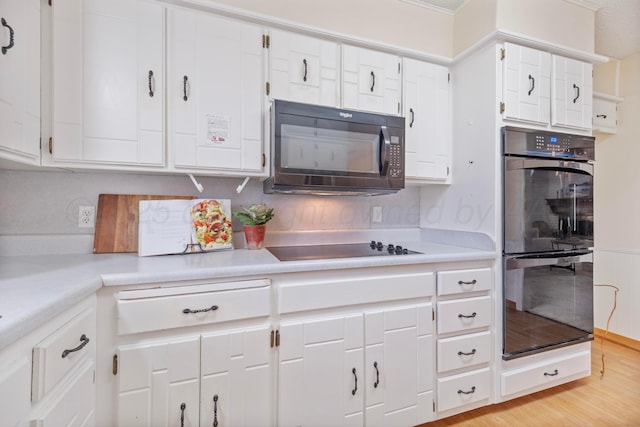kitchen featuring white cabinetry, light countertops, and black appliances