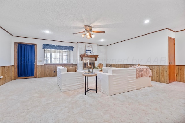 carpeted living room with wainscoting, wooden walls, ceiling fan, and a textured ceiling