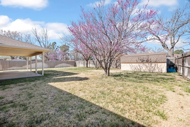 view of yard with an outdoor structure, a fenced backyard, a storage shed, and a patio