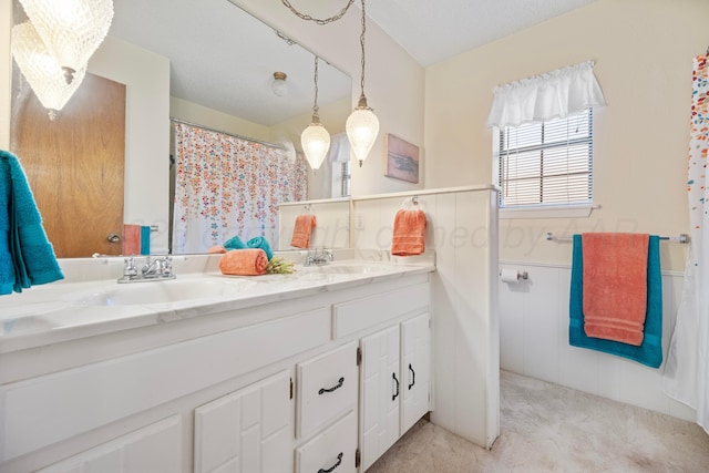 full bathroom with double vanity, wainscoting, a sink, and a shower with shower curtain