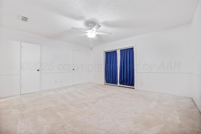 empty room with visible vents, ceiling fan, carpet, and a textured ceiling