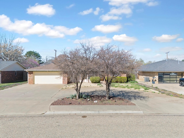 view of front facade featuring curved driveway, fence, an attached garage, central AC unit, and brick siding