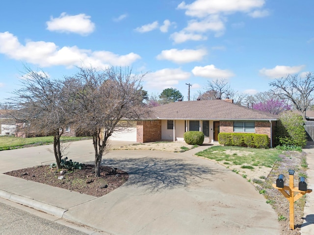 view of front of home featuring a chimney, a garage, curved driveway, and brick siding