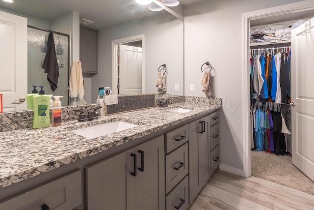 5904 Nancy Ellen St, Amarillo, TX 79119 - bathroom featuring double vanity, a spacious closet, a shower stall, and wood finished floors