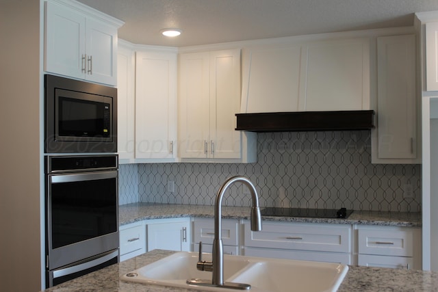 kitchen featuring white cabinetry, sink, tasteful backsplash, exhaust hood, and appliances with stainless steel finishes