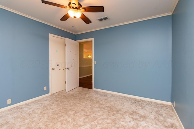 unfurnished room with visible vents, crown molding, baseboards, a ceiling fan, and carpet floors