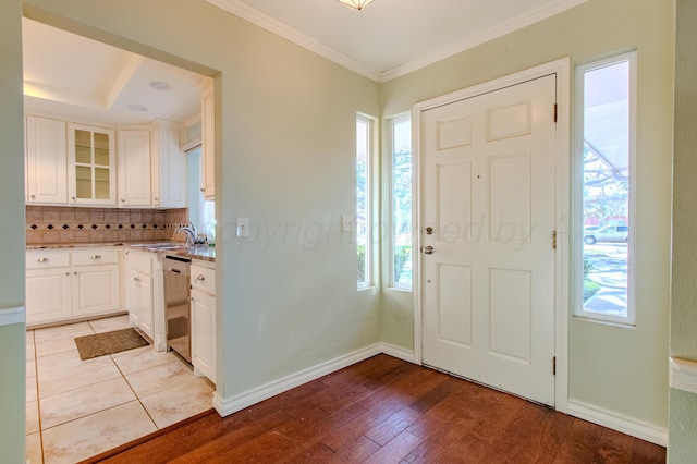 entrance foyer featuring baseboards, ornamental molding, and light wood-style flooring