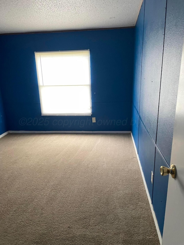 unfurnished room with carpet floors, a textured ceiling, and baseboards