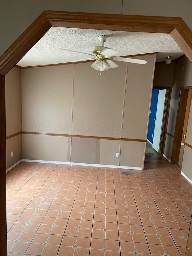 empty room with baseboards, a ceiling fan, and a textured ceiling