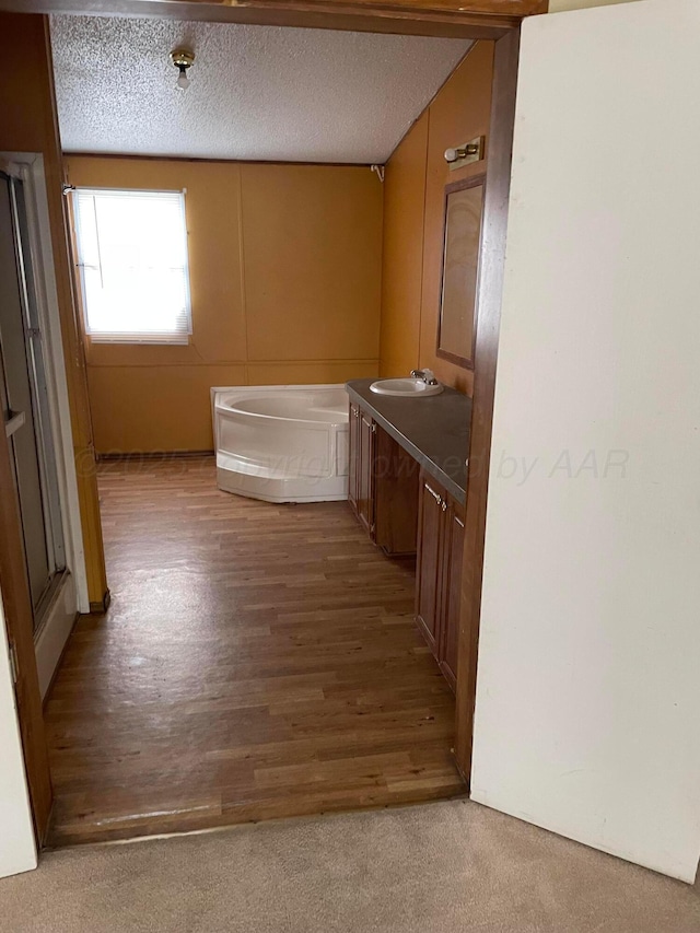 full bathroom with carpet, wood finished floors, vanity, and a textured ceiling