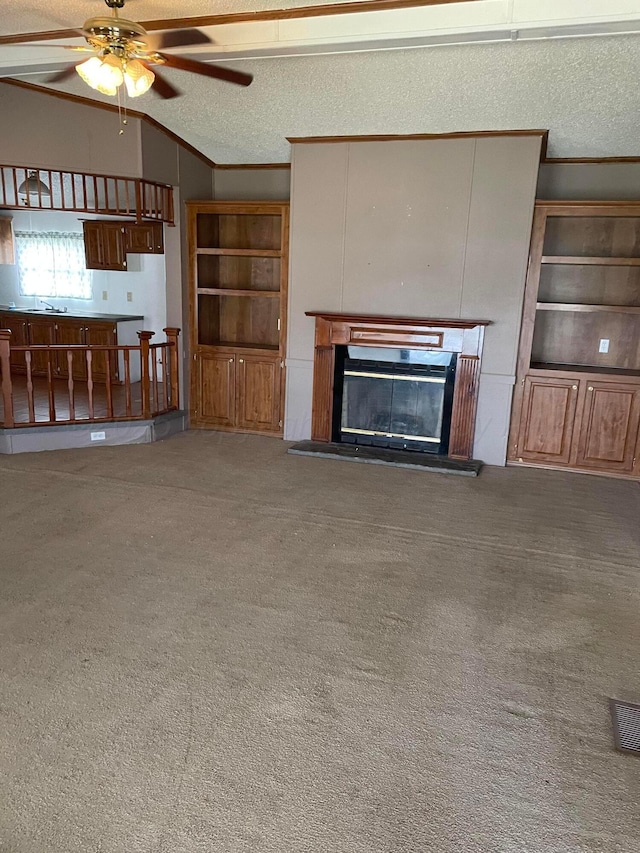 unfurnished living room with ceiling fan, lofted ceiling, ornamental molding, and carpet flooring
