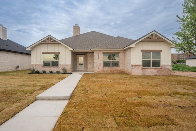 5505 Sheridan St, Amarillo, TX 79119 - view of front of property with board and batten siding, a front yard, a chimney, and brick siding