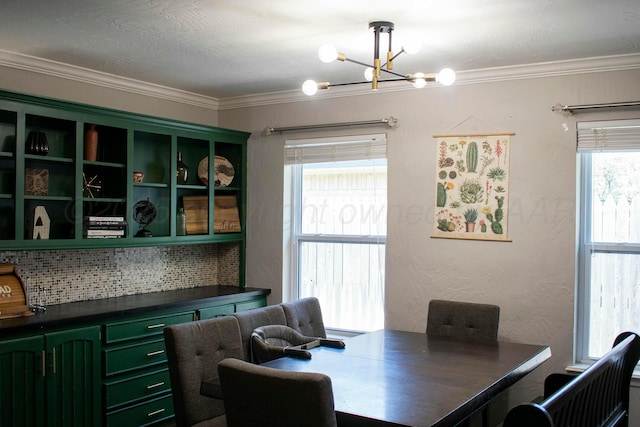 dining space featuring an inviting chandelier, ornamental molding, and a textured wall
