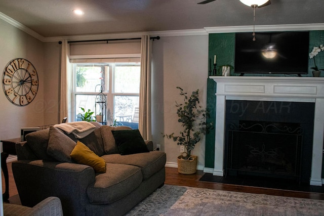 living area featuring baseboards, ornamental molding, a premium fireplace, ceiling fan, and wood finished floors