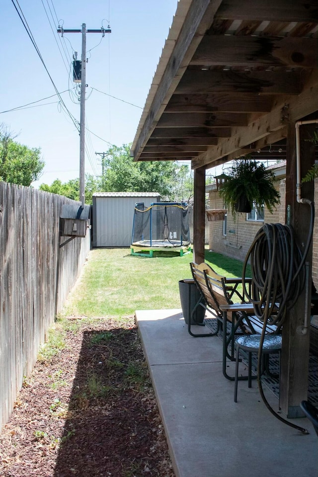 view of yard with a patio, a trampoline, and a fenced backyard