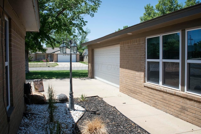view of side of property with a garage, driveway, and brick siding